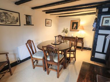 A dining room with a round table and four chairs under exposed wooden beams at Nurses Cottage in Hawkshead