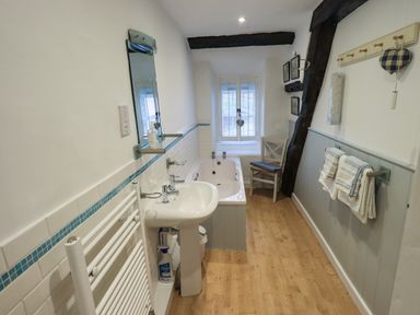 A bathroom with a sink bathtub chair towels and a window with wooden blinds at Nurses Cottage in Hawkshead