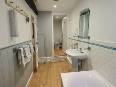 A bathroom with a sink mirror towels and a toilet visible through a door at Nurses Cottage in Hawkshead