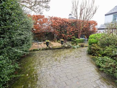A garden area with paved ground seating bench and bushes at Nurses Cottage in Hawkshead