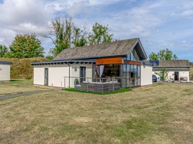 A modern house with a patio and outdoor seating on a grassy lawn at Wood Sage in Bamburgh