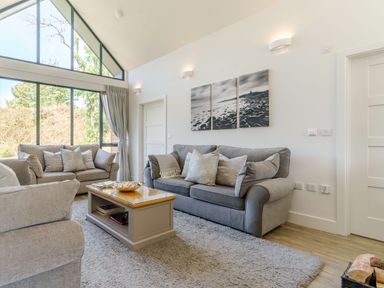 A living room with sofas a coffee table and large windows at Wood Sage in Bamburgh