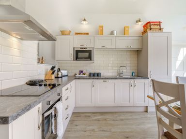 A kitchen with white cabinets and tiled backsplash at Wood Sage in Bamburgh