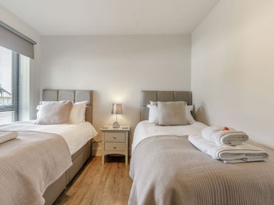 A bedroom with two single beds separated by a nightstand with a lamp at Wood Sage in Bamburgh