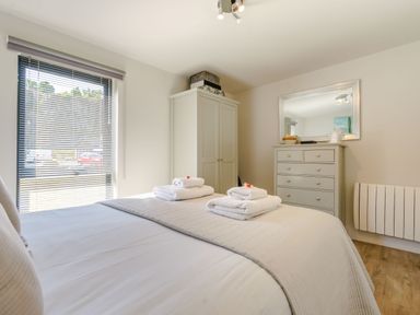 A bedroom with a bed with folded towels a wardrobe a chest of drawers and a window with blinds at Wood Sage in Bamburgh