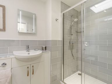 A bathroom with a sink and mirror next to a glass-enclosed shower at Wood Sage in Bamburgh