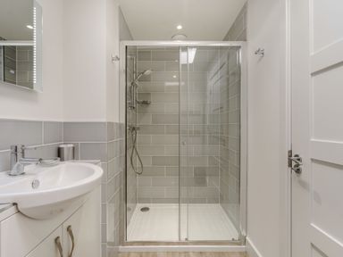 A bathroom with a shower enclosure and a sink with cabinet at Wood Sage in Bamburgh