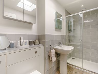 A bathroom with a sink a shower cabin and storage cabinet with toiletries at Wood Sage in Bamburgh