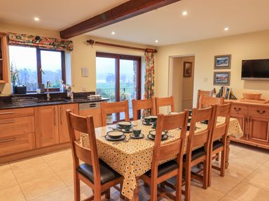 A kitchen dining area with a wooden table set with dishes and chairs and cabinets at Low House in Ullswater