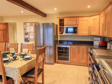 A kitchen with wooden cabinets stainless steel appliances and a dining table with chairs at Low House in Ullswater