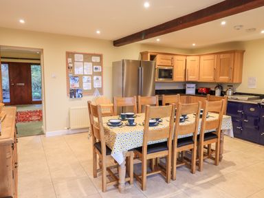 A kitchen with wooden dining table and chairs set with plates and cups at Low House in Ullswater
