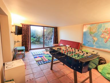 A game room with a foosball table colorful chairs a couch a world map and a sliding glass door at Low House in Ullswater