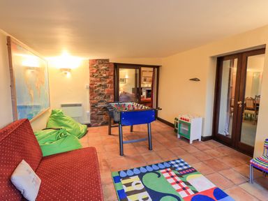 A game room with a foosball table red couch green bean bags and a colorful rug at Low House in Ullswater