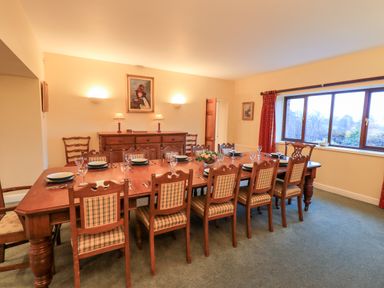 A dining room with a large wooden table set with plates and glasses and wooden chairs at Low House in Ullswater