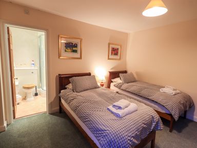 A bedroom with two single beds and an open door to a bathroom at Low House Ullswater