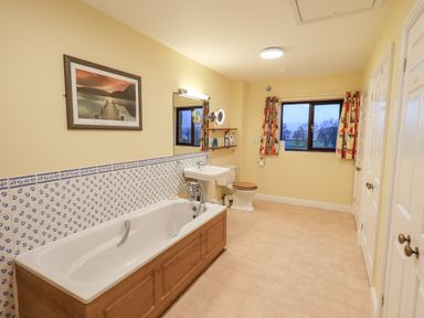 A bathroom with a bathtub sink toilet window and colorful curtains at Low House in Ullswater