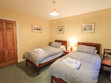 A bedroom with two single beds with checked bedding and towels on top at Low House in Ullswater
