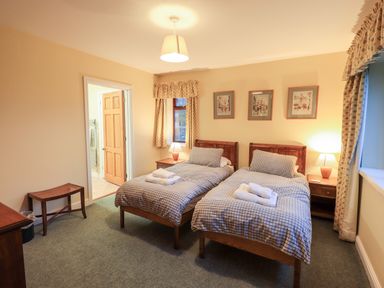 A bedroom with two single beds lamps and framed pictures on the wall at Low House in Ullswater