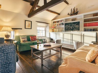A living room with sofas a coffee table bookshelves and exposed wooden beams at High Lindeth in Bowness
