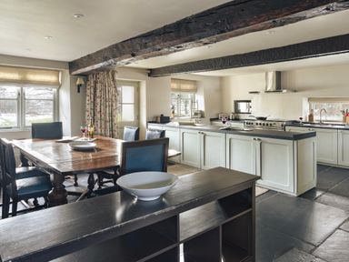 A kitchen with wooden dining table and chairs granite floor and exposed wooden beams at High Lindeth in Bowness