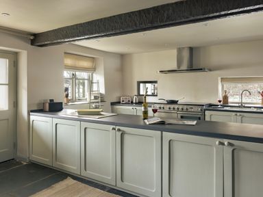 A kitchen with a countertop holding a bottle and a glass of wine at High Lindeth in Bowness