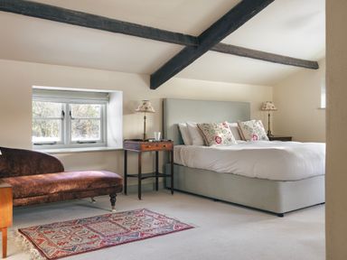 A bedroom with a bed two bedside tables with lamps a window and a chaise lounge at High Lindeth in Bowness
