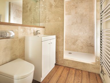 A bathroom with a toilet sink cabinet shower area and a towel radiator at High Lindeth in Bowness
