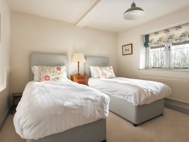 A bedroom with two single beds and a window with floral blinds at High Lindeth in Bowness