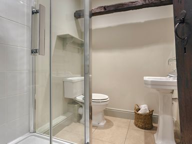 A bathroom with a shower enclosure a toilet a pedestal sink and a basket with towels at High Lindeth in Bowness