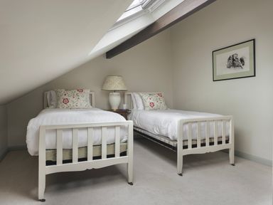 A bedroom with two single beds and a lamp on a side table at High Lindeth in Bowness