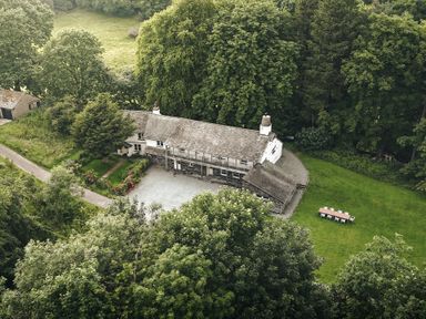 An aerial view of a house with a lawn and trees at High Lindeth in Bowness