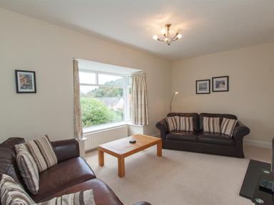 A living room with two brown leather sofas striped cushions wooden coffee table and a large window at The Haven in Keswick
