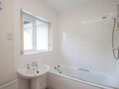 A bathroom with a bathtub sink and window at The Haven in Keswick