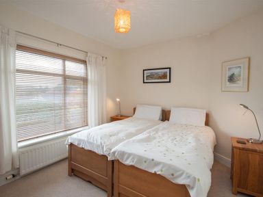 A bedroom with two single beds wooden bedside tables and a large window at The Haven in Keswick
