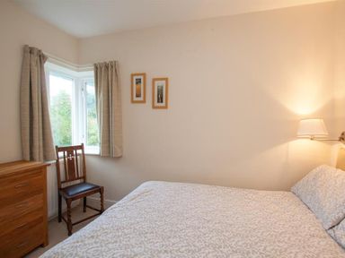 A bedroom with a bed a wooden chair a wooden chest of drawers and two framed pictures on the wall at The Haven in Keswick