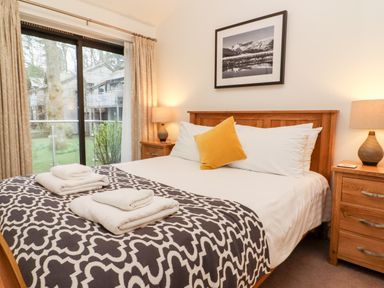 A bedroom with a patterned blanket on a bed and towels on top at Fir Howe in Skelwith