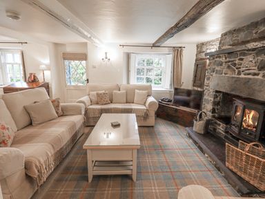 A living room with two sofas a coffee table a fireplace and a television at Syke Cottage in Hawkshead