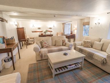 A living room with two sofas a coffee table armchairs wooden furniture and lamps at Syke Cottage in Hawkshead