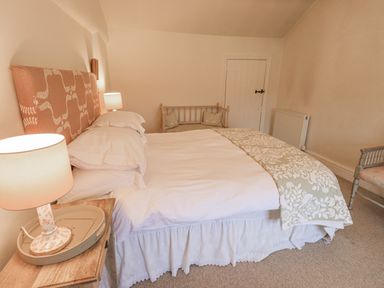 A bedroom with a bed pillows and lamps on a wooden nightstand at Syke Cottage in Hawkshead