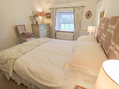 A bedroom with a bed a chest of drawers a chair and a window at Syke Cottage in Hawkshead