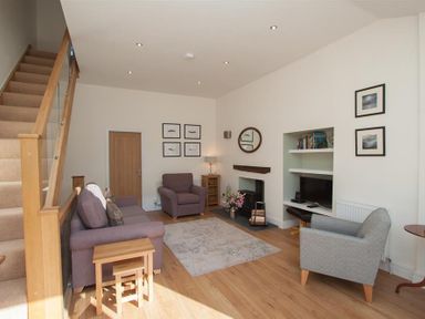 A living room with two armchairs a sofa a rug and a staircase at Mylnbeck in Bowness