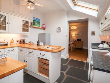 A kitchen with white cabinets wooden countertops and slate flooring at Hazeldene in Ambleside