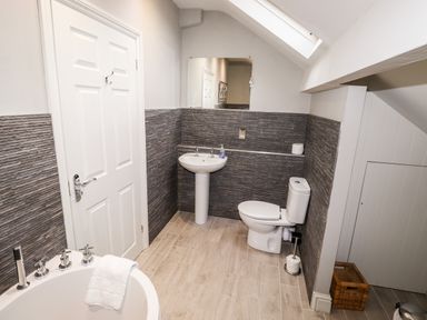 A bathroom with a bathtub a pedestal sink and a toilet at Hazeldene in Ambleside