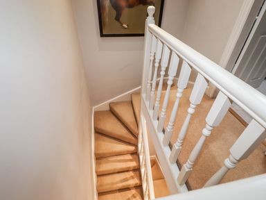 A staircase with beige carpet and white wooden railing in a residential interior at Hazeldene in Ambleside