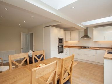A kitchen with wooden dining table and chairs white cabinets and built in oven at Fell End in Keswick