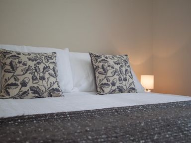 A bed with two patterned pillows and a bedside lamp at Fell End in Keswick
