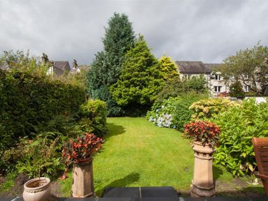A garden with green lawn surrounded by various trees and shrubs at Fell End in Keswick