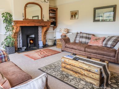 A living room with a wooden fireplace a brown sofa and a wooden coffee table at The Stables in Ambleside