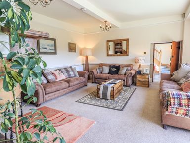 A living room with three sofas a wooden chest as a coffee table and a floor lamp at The Stables in Ambleside