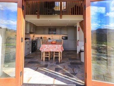 A kitchen with a dining table and chairs open to an outdoor view at The Stables in Ambleside